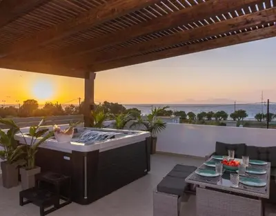 a patio with a hot tub and a grill at ODYSSEA Top View & Hot Jacuzzi Front Beach in Kremasti