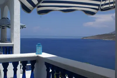 a blue cup sitting on a balcony overlooking the ocean at Annas Studios in Livadia