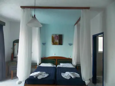 a bedroom with two beds with white curtains at Annas Studios in Livadia