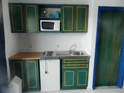 a kitchen with green cabinets and a sink and a microwave at Annas Studios in Livadia