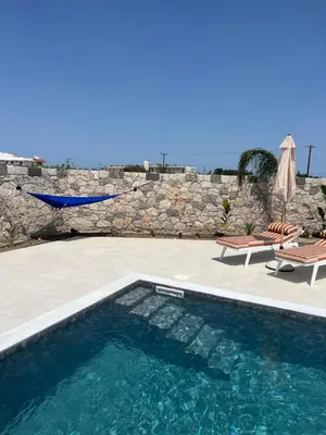 a swimming pool next to a stone wall at Cora May Central Villa with private pool 200m to the beach in Faliraki