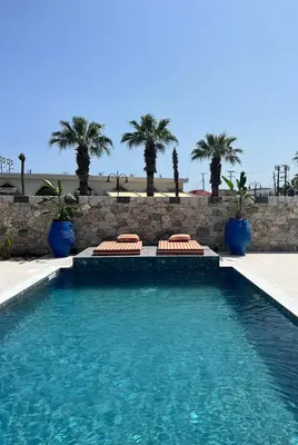 a swimming pool with chairs and palm trees at Cora May Central Villa with private pool 200m to the beach in Faliraki