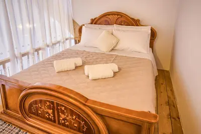 a large wooden bed with two towels on it at Stone Arch in Malona Village