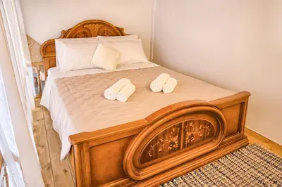 a bedroom with a wooden bed with two pillows at Stone Arch in Malona Village