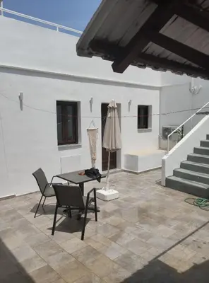 a room with a table and chairs and stairs at Lindos Alley in Líndos