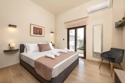 a bedroom with a bed and a chair and a window at Adelais Luxury City Apartment Rhodes in Rhodes Town