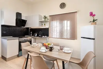 a kitchen with a table and chairs and a white refrigerator at Adelais Luxury City Apartment Rhodes in Rhodes Town