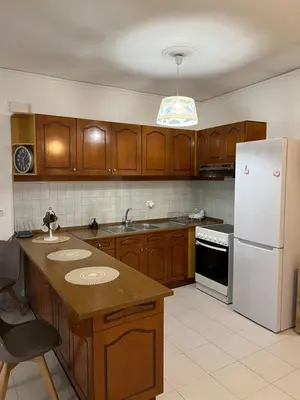 a kitchen with wooden cabinets and a white refrigerator at Johannes House in Afantou