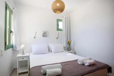 a white bedroom with a bed with two towels on it at Villa Asteria in Gennadi