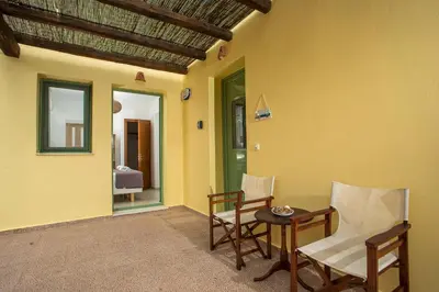 a living room with a table and chairs and a room with yellow walls at Villa Asteria in Gennadi