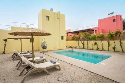 a group of chairs and an umbrella and a swimming pool at Villa Asteria in Gennadi