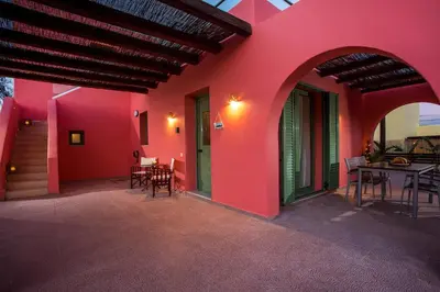 a house with a red wall with chairs and a table at Villa Selene in Gennadi