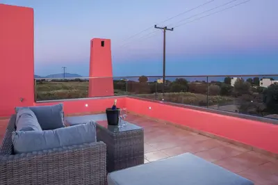 a balcony with a couch and a table and a red wall at Villa Selene in Gennadi