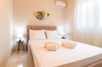 a bedroom with a large white bed with two pillows at Nikargy Luxury Apartments in Koskinou