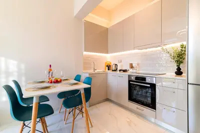 a white kitchen with a table and chairs at Nikargy Luxury Apartments in Koskinou