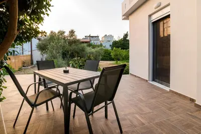 a wooden table and chairs on a patio at Nikargy Luxury Apartments in Koskinou