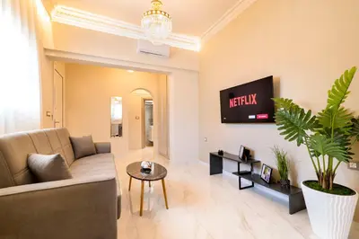 a living room with a couch and a tv on a wall at Nikargy Luxury Apartments in Koskinou