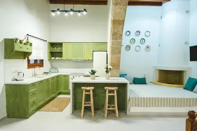 a kitchen with green cabinets and a kitchen island with stools at Aesthisis Sensational Accommodation Archangelos in Archangelos