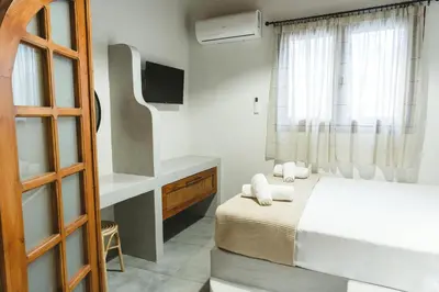a bedroom with a bed and a desk and a television at Aesthisis Sensational Accommodation Archangelos in Archangelos