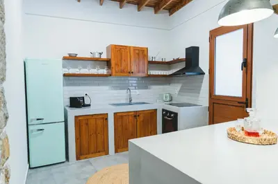 a kitchen with wooden cabinets and a white refrigerator at Aesthisis Sensational Accommodation Archangelos in Archangelos