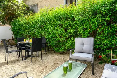a patio with chairs and a table in front of a hedge at Alchadef Park Apartment in Rhodes Town