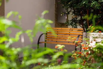 a wooden bench sitting in a garden with flowers at Alchadef Park Apartment in Rhodes Town