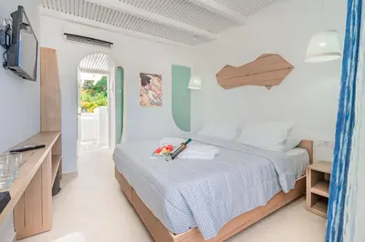 a white bedroom with a bed and a tv at Aloe Hotel - Adults Only in Faliraki