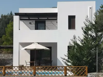 a white house with a table and an umbrella at 3 Bed Villa In Lardos Village in Lardos