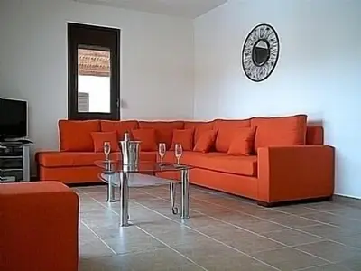 a living room with an orange couch and a table at 3 Bed Villa In Lardos Village in Lardos
