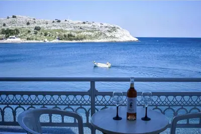 a table with two wine glasses and a boat in the water at Haraki Sunset Apartment in Haraki