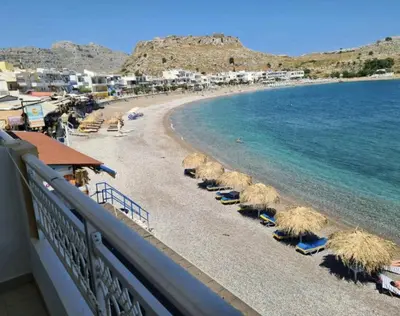a beach with straw umbrellas and the ocean at Haraki Sunset Apartment in Haraki