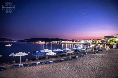 a beach with blue and white umbrellas and the water at Haraki Sunset Apartment in Haraki