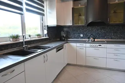 a kitchen with white cabinets and a sink and a window at GianAngelo Holiday Villa in Kremasti