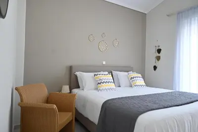 a white bedroom with a bed and a chair at GianAngelo Holiday Villa in Kremasti