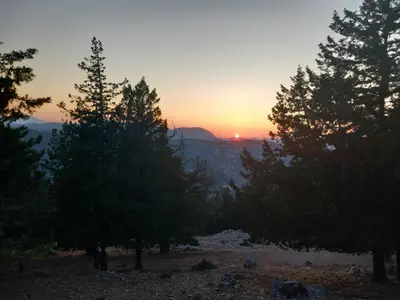 a sunset in the mountains with trees in the foreground at Kolymbia summer holidays in Kolimbia