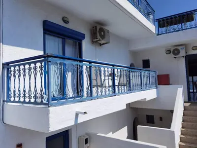 a white building with a blue balcony and stairs at Marinas Studios in Livadia