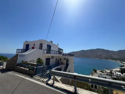a white building with the ocean in the background at Marinas Studios in Livadia
