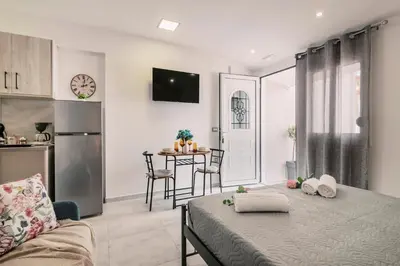 a room with a bed and a kitchen with a table at Fay's Suites in Ialyssos