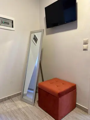 a room with a mirror and a ottoman and a television at Jz boutique 1 in Rhodes Town