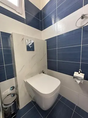 a bathroom with a white toilet and blue stripes at Jz boutique 1 in Rhodes Town