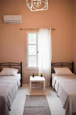 two beds in a room with a window and a table at Ixia Manor House in Ixia