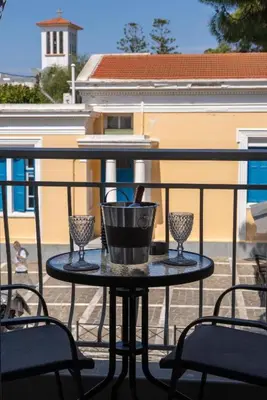 a table on a balcony with two glasses on it at Charavgi Apartment 1 in Kremasti