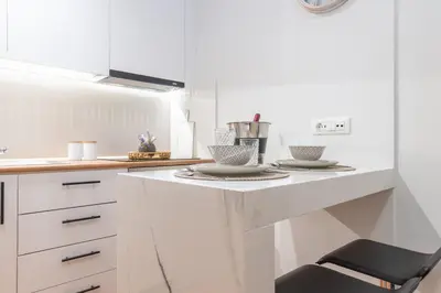 a white kitchen with a counter with two plates and a chair at Charavgi apartment 2 in Kremasti