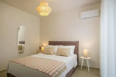a white bedroom with a bed and a mirror at Villa Ariadne in Gennadi