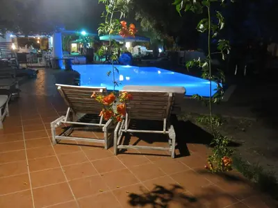 a table and chairs next to a pool at night at Gorgona Studios in Faliraki