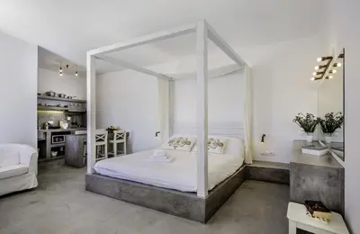 a bedroom with a white canopy bed and a kitchen at Lindian Pearl in Líndos