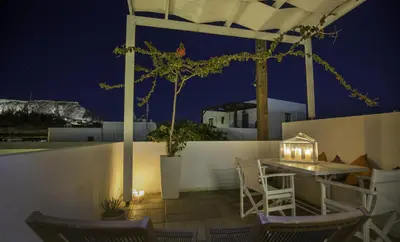 a patio with a table and chairs at night at Lindian Pearl in Líndos