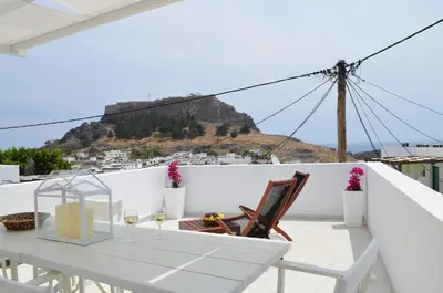 a white table and chair on a balcony with a hill at Lindian Pearl in Líndos
