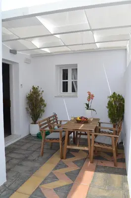 a room with a wooden table and benches and a white wall at Lindian Pearl in Líndos