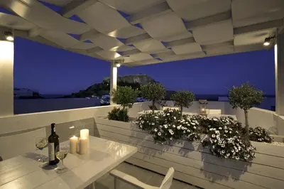 a table with candles and a bottle of wine on a balcony at Lindian Pearl in Líndos